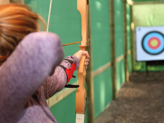 Lady about to shoot an arrow at an archery target 